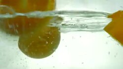 Orange cut in half drop in the water. Close up. Slow motion. Stock Footage