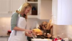 Housewife in kitchen grates pepper onto dish Stock Footage