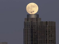 Shot of the moon rising over a building in the Manhattan Skyline in New York City. Stock Footage
