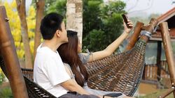 Smiling couple taking selfie on their phone in a park Stock Footage
