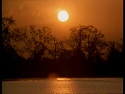 WA Orange sunlight reflecting on water at dusk, bright sun in sky, India Stock Footage