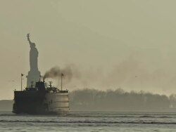 WS Statue of Liberty in Manhattan and ferry is seen going past at evening / New York, United States Stock Footage