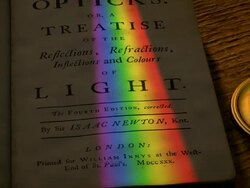 Frontispiece of Isaac Newton's 'Opticks', with a spectrum of light cast upon it by a rotating prism above. Stock Footage