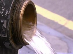 Water flows from a fire hydrant as a firefighter walks by. Stock Footage
