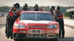 Pit-crew team pushes race-car Stock Footage