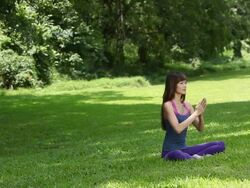 WS Asian woman sitting on grass in lotus position practicing Yoga Stock Footage