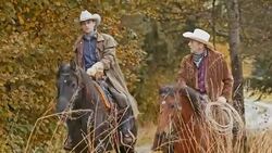 Two cowboys talking while riding their horses Stock Footage