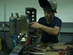 Push in on man working at his metal workshop table. Stock Footage