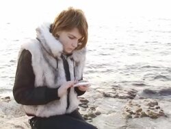 Girl on the coast with phones Stock Footage