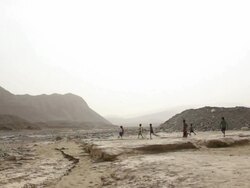 Children playing soccer in the desert Stock Footage