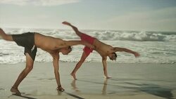 Young men doing cartwheels on beach Stock Footage