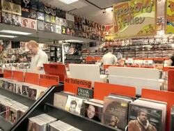 WS TS customers in record store digging through bins of second hand vinyl records and CDs / Palm Desert, California, USA Stock Footage