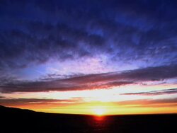 A person walking in the desert, with the sunset painting the sky.  Stock Footage