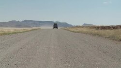 A safari jeep speeds along a road in the Namib Desert. Stock Footage