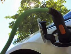 HD: Charging An Electric Car Under Green Trees Stock Footage