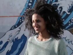 Young woman with curly hair looking into camera, smiling, laughing in sunshine Stock Footage