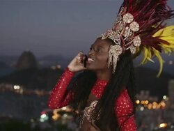 MS A passista carnival dancer uses a mobile phone with Rio skyline in background / Rio de Janeiro, Brazil Stock Footage