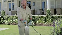 Senior man watering flowers in garden with hose Stock Footage