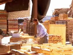 carpentry workshop in pallet manufacturing plant as worker staples wooden slats to complete standard size wooden pallet  / Fontana, California, USA Stock Footage