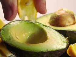  CU Hand squeezing fresh lemon juice from lemon wedge on avocado / Los Angeles, California, United States Stock Footage