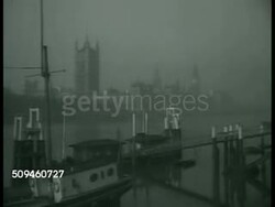 1938: LONDON, ENGLAND: WS (FOGGY) Houses of Parliament & Clock Tower w/ Thames River & docked boats FG. MS British Prime Minister Neville Chamberlain speaking (no SOT) in front of bookcase. WWII Instructional Video