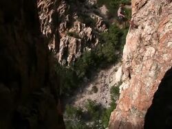 Handheld shot of a rock-climber descending a craggy cliff. Stock Footage