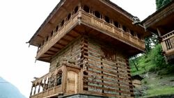 Pan up shot of ornately carved wooden Hindu Temple with ethnic village woman sitting front of temple. Stock Footage