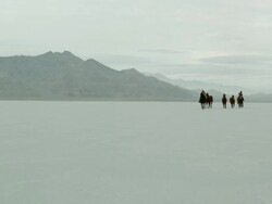 Horses running with cowboys riding across salt flats. Stock Footage