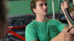 Bike mechanic in repair shop places bicycle wheel on truing stand, tightens grip, and spins Stock Footage