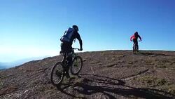 Mountain bikers ascend steep mountain slope, to summit Stock Footage