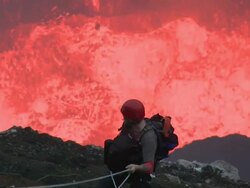 Lava erupts from volcano behind climber, Marum Volcano, Ambrym Island, Vanuatu Stock Footage