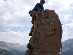 Climbers ascend to summit of pinnacle, pull rope tight to leader Stock Footage
