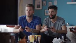 Guys sitting on couch playing video games and cheering Stock Footage