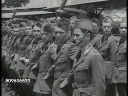 1940: ARMY AIR FORCE: WS Soldiers standing on airfield. Officer at desk handing papers. Army pilots (young adults) standing  in formation, saluting, leaving. DUTCH OFFICIALS MEET: Officials in meeting, sitting at table, talking. Instructional Video