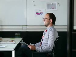 MS DS businessman sitting in office working on digital tablet in discussion/Seattle, Washington, USA Stock Footage