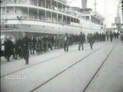 1938: BRITISH MANDATE PALESTINE: JERUSALEM: Angled WS Jewish refugees, displace persons, men, women, walking down dock w/ soldiers in uniform escorting, large passenger ship docked BG. TD WS Same refugees walking curve off dock area.  Instructional Video