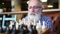 the elderly man with the appearance of the professor plays chess Stock Footage
