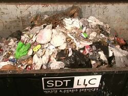 Medium Shot High Angle - Trash is dumped from above into garbage receptacle, some spills over / New Orleans Louisiana Stock Footage