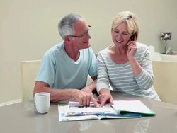 Mature couple looking at magazine, woman on mobile phone Stock Footage