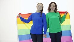 Beautiful young adult female couple holding hands and gay pride flag Stock Footage