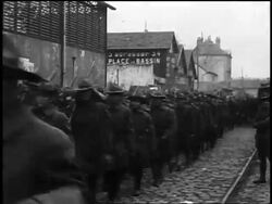 B/W 1910s line of American soldiers in uniforms carrying guns marching past camera in French town Stock Footage