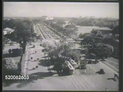 1937: PHILIPPINES ISLANDS: VS Automobiles moving along on wide lane city streets, dome building w/ Filipino pedestrians & vehicles on streets below, vehicles moving across bridge, boats in river, buildings BG. Republic of the Philippines Instructional Video