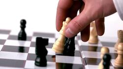 White chess piece knocking over a black one Stock Footage