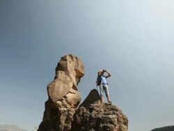 Young man standing on a cliff of mountain and looking through a binocular  Stock Footage