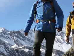 Slo-mo pan of father & son descending trail, mountains behind Stock Footage