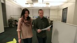 Businessman confers with trendy assistant walking down office hallway (tracking shot) Stock Footage