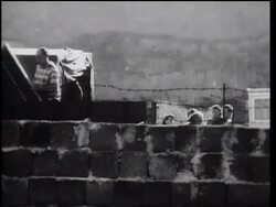 B/W 1961 PAN man loading belongings onto truck behind Berlin Wall / East Berlin, Germany Stock Footage