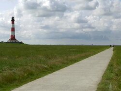 WS View of Westerhever lighthouse from grass field with walking trails and clouds moving over / Westerhever, Schleswig Holstein, Germany Stock Footage