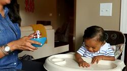 MS Smiling mother feeding infant son in highchair in dining room Stock Footage