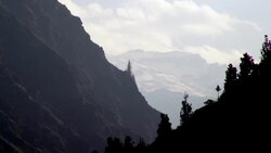 Pan shot of silhouette of trees along mountainside with snow capped Himalayan Mountains in background. Stock Footage